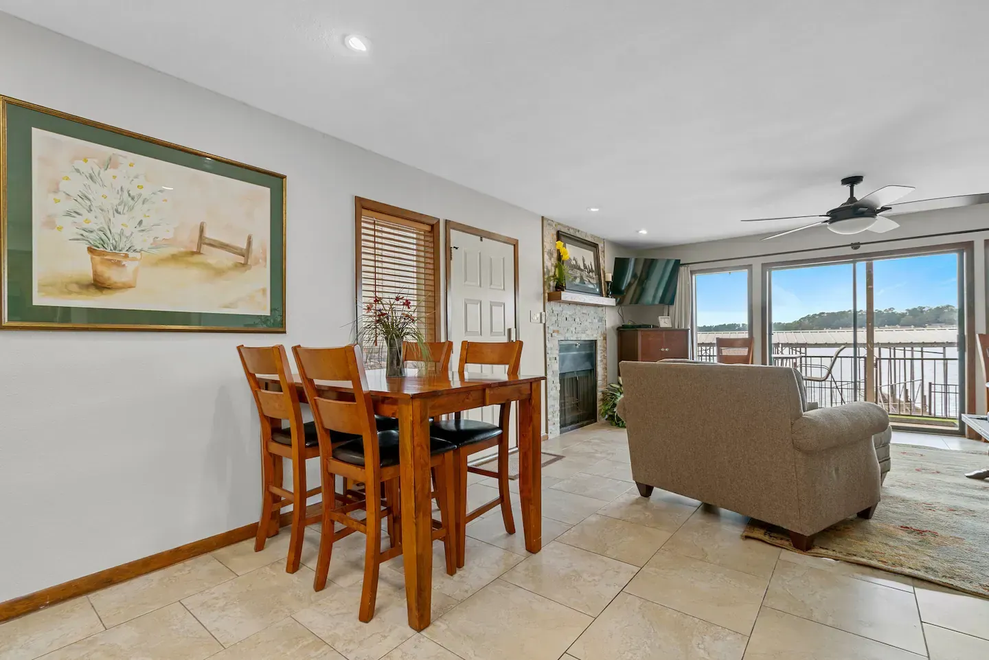 A living room with a dining table and chairs and a painting on the wall.