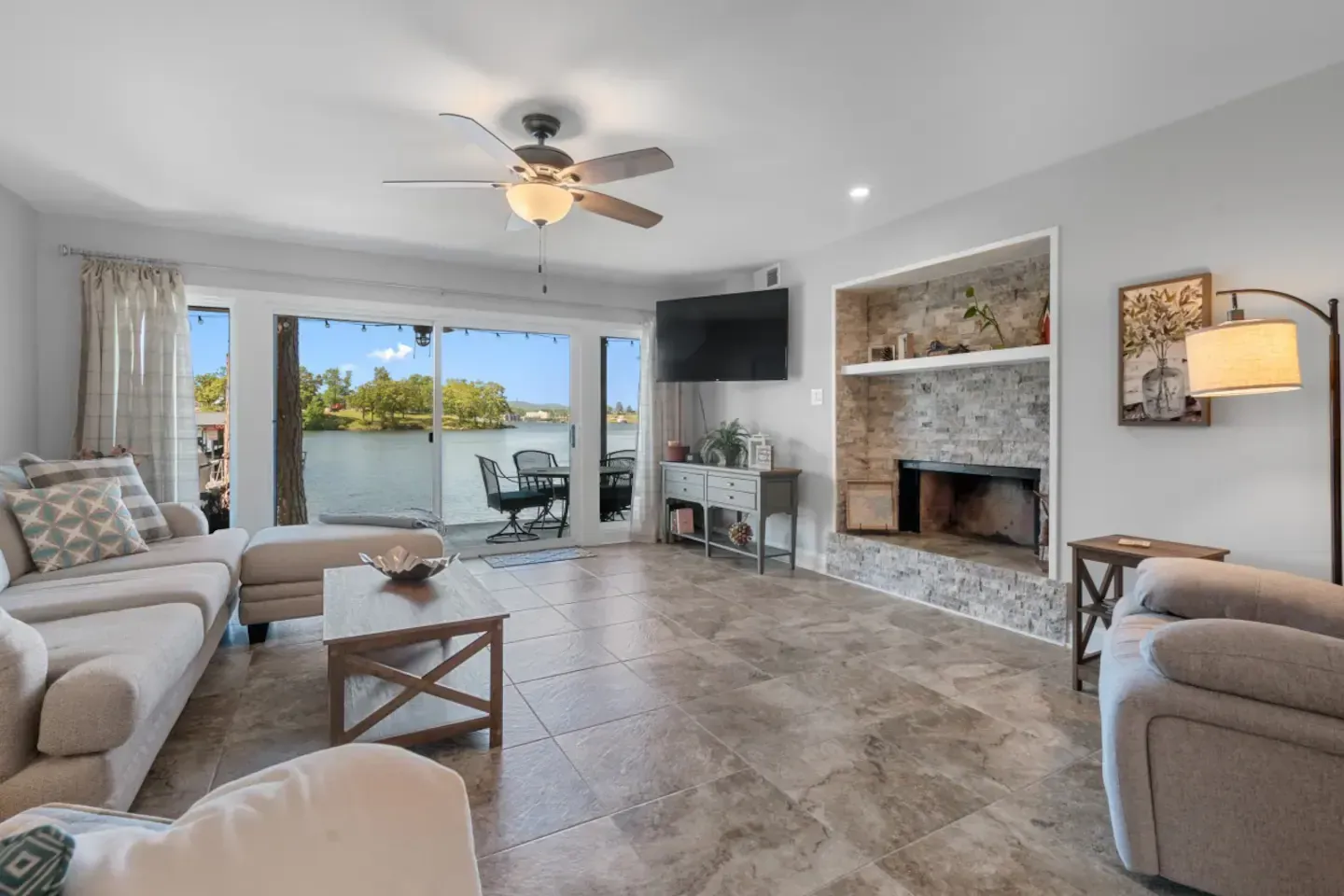 A living room with a fireplace , couch , chairs and a ceiling fan.