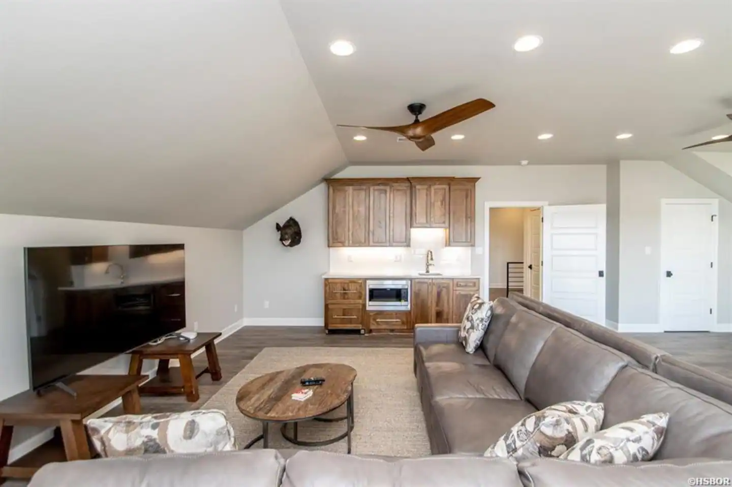 A living room with a couch , table , television and ceiling fan.