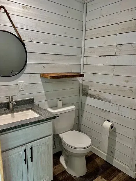 A bathroom with a toilet , sink and mirror.