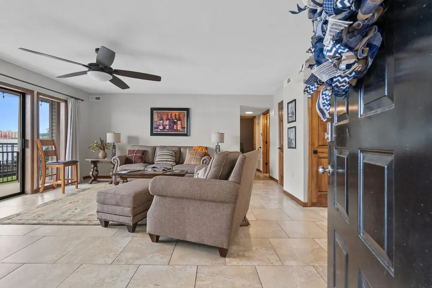 A living room with a couch , chair , ottoman and ceiling fan.