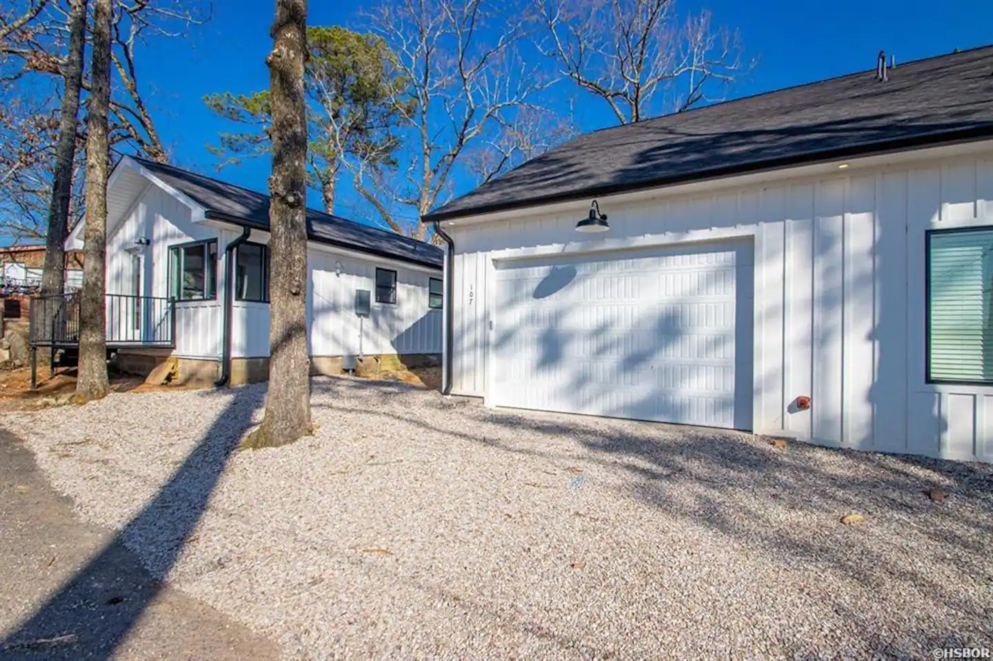 A white house with a garage and trees in the background.