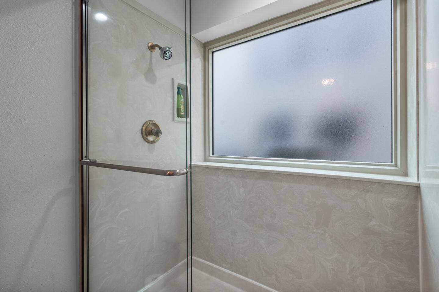 A bathroom with a glass shower door and a window.