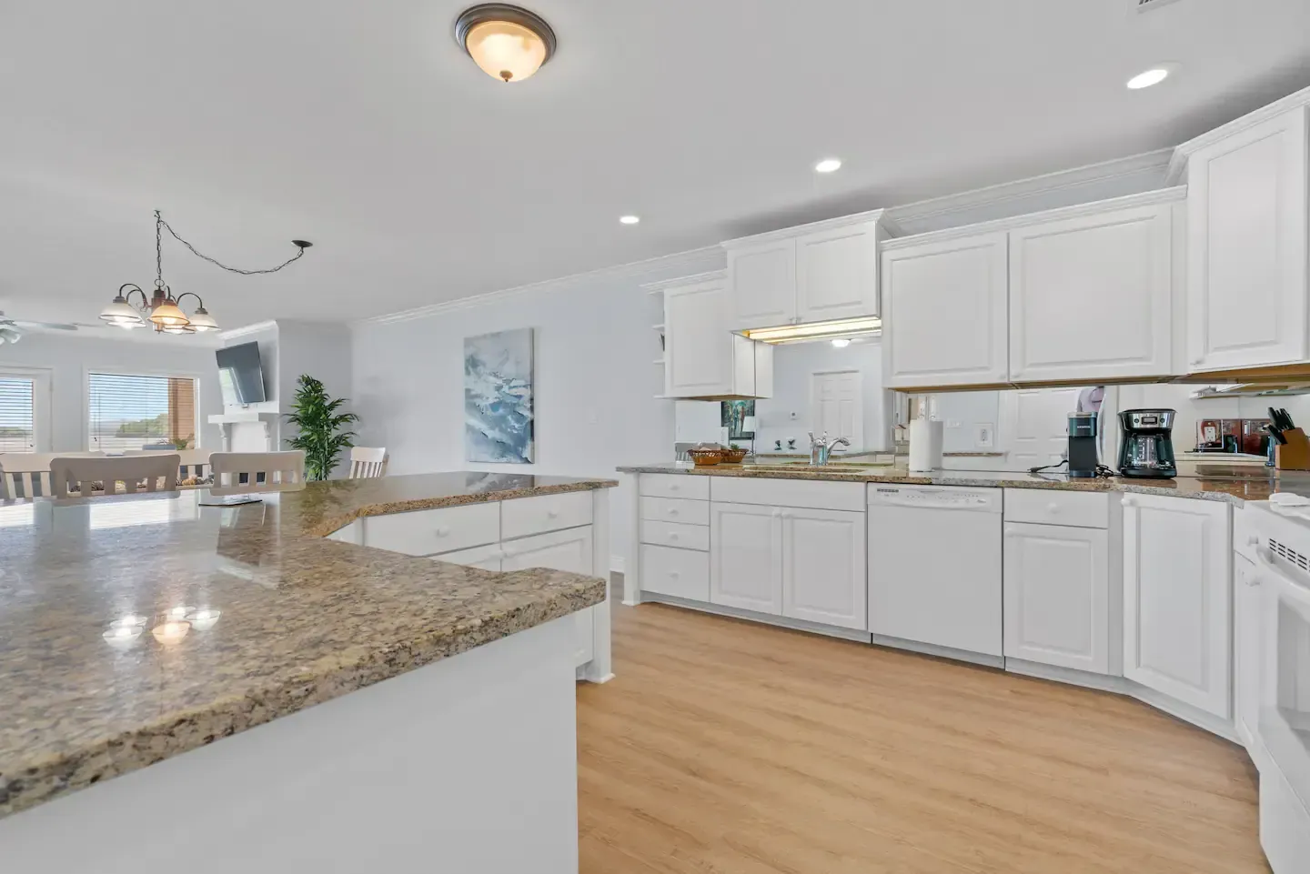 A kitchen with white cabinets and granite counter tops.