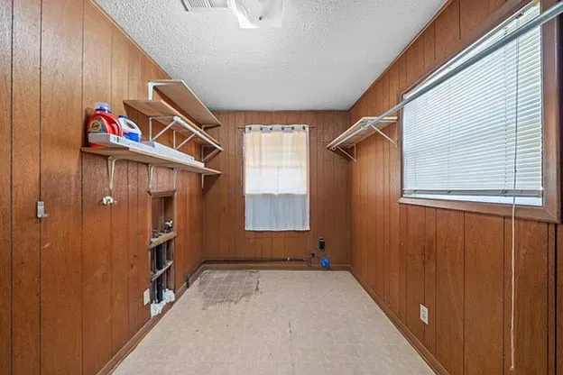 An empty room with wood paneling and a window.