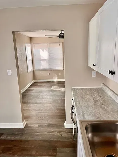 A kitchen with a sink , cabinets , and a window.