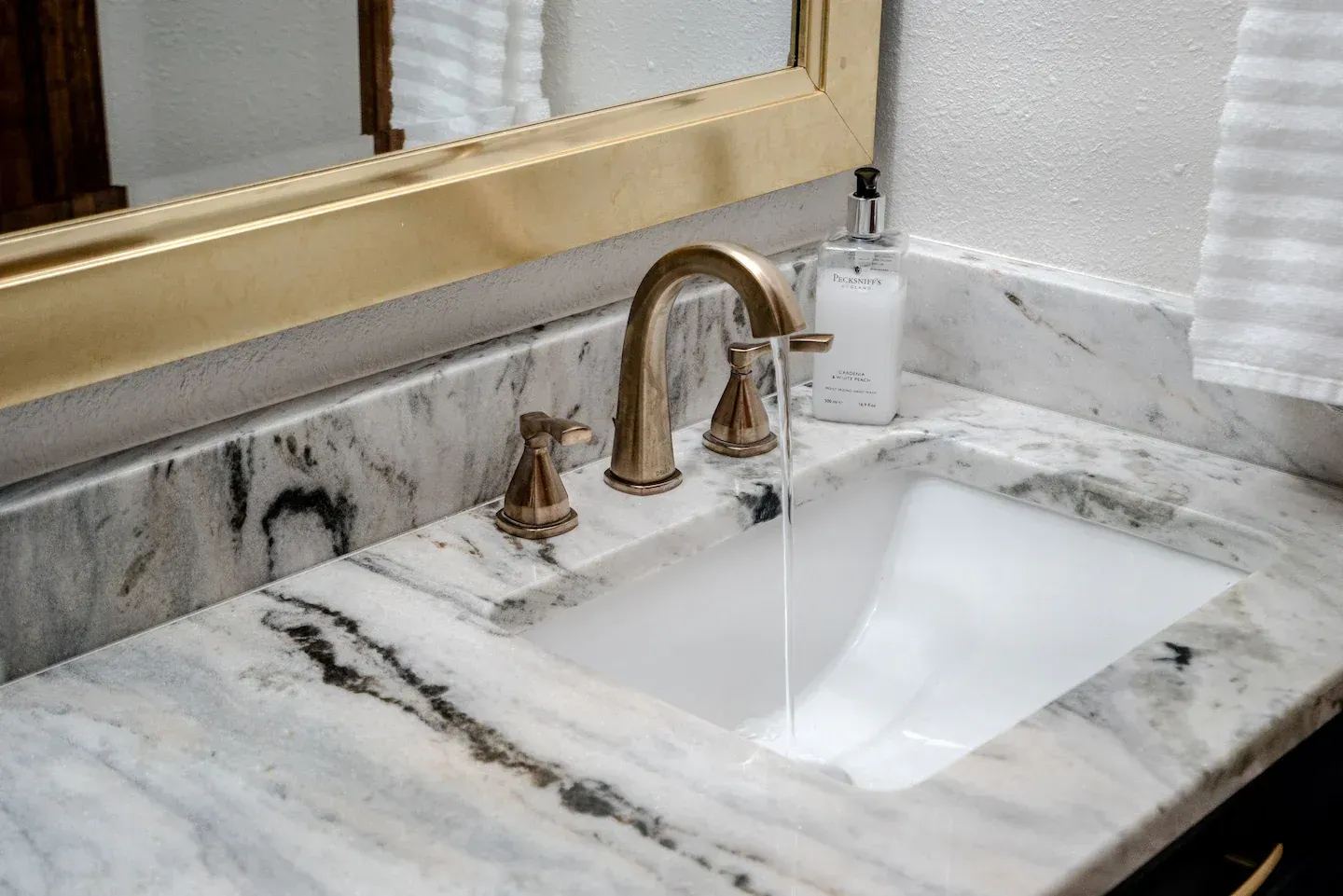 A bathroom sink with a marble counter top and a mirror.