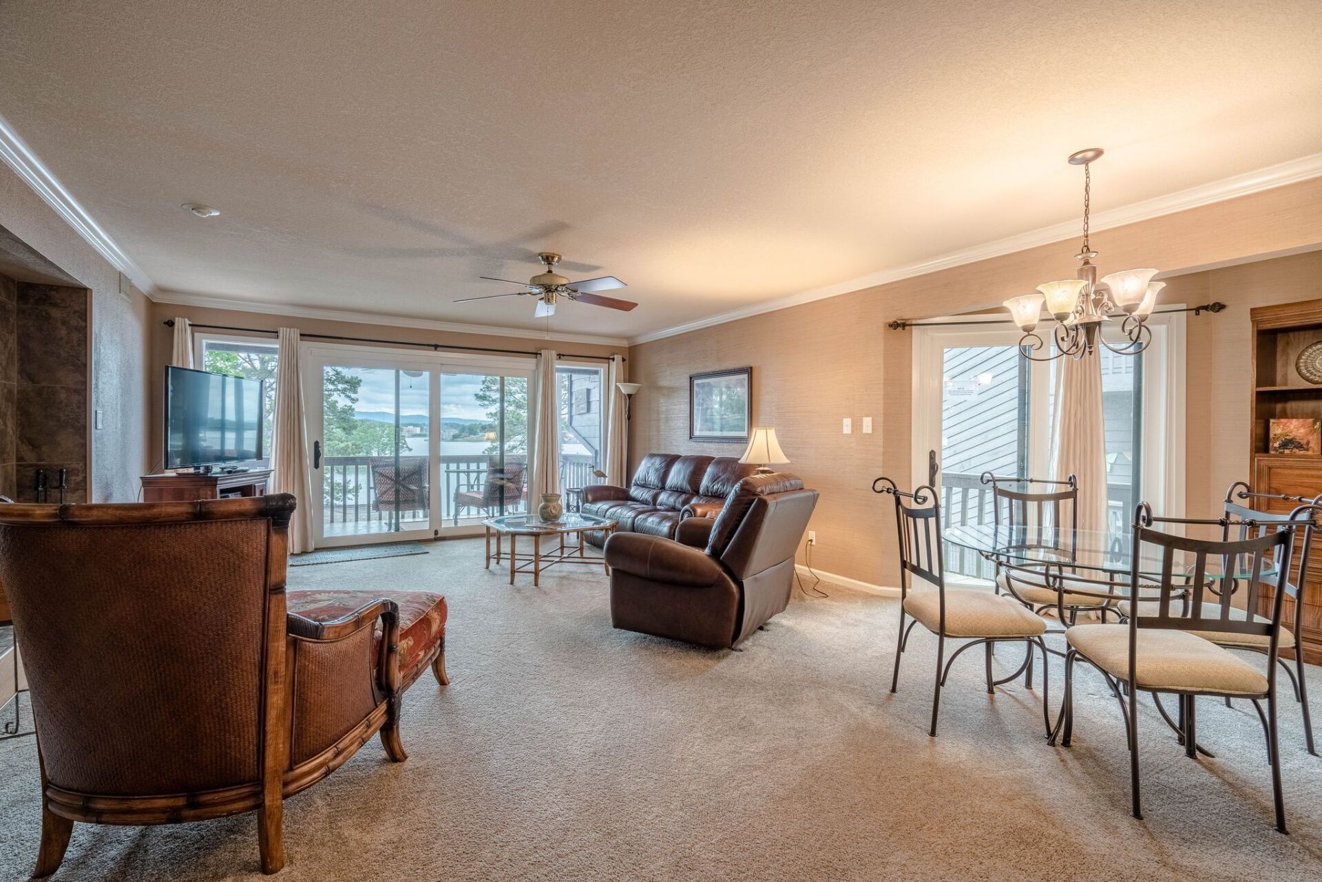 A living room with a couch , chairs , a table and a ceiling fan.