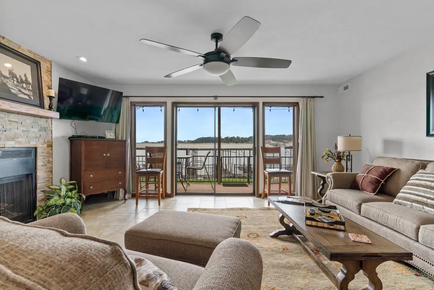 A living room with a couch , chair , coffee table , fireplace and ceiling fan.