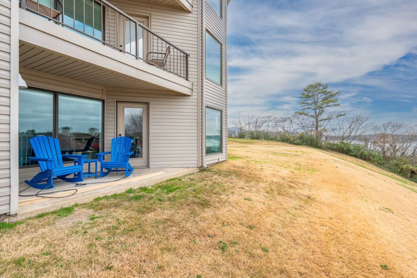 There are two blue chairs on the patio of a house.