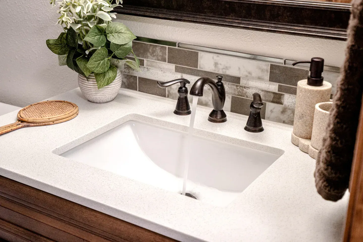 A bathroom sink with a plant and a mirror on the counter.