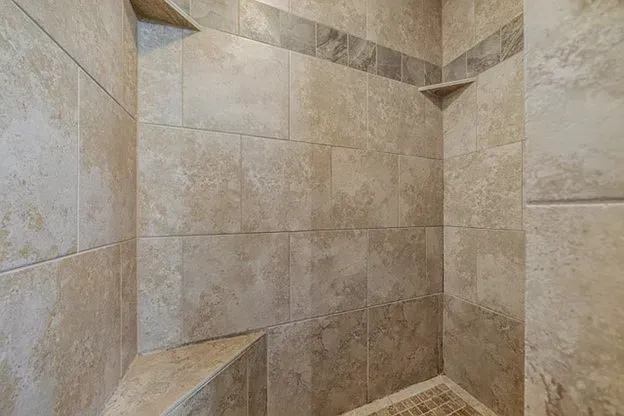 A shower with tiled walls and shelves in a bathroom.