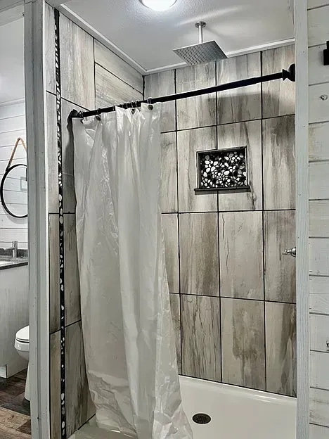 A bathroom with a shower curtain and a shower head.