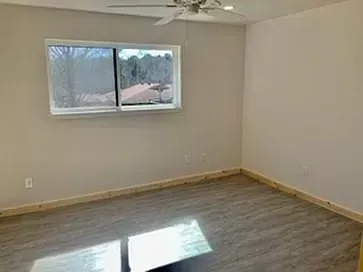 An empty room with a ceiling fan and a window.