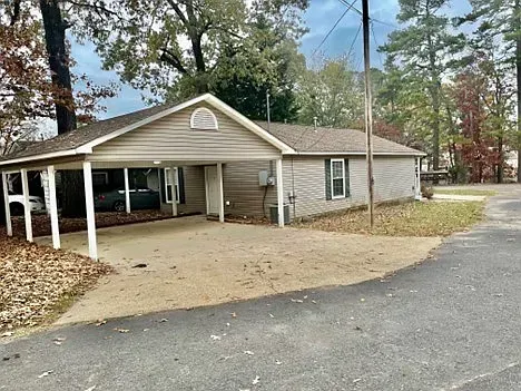 A small house with a carport and a car parked in front of it.