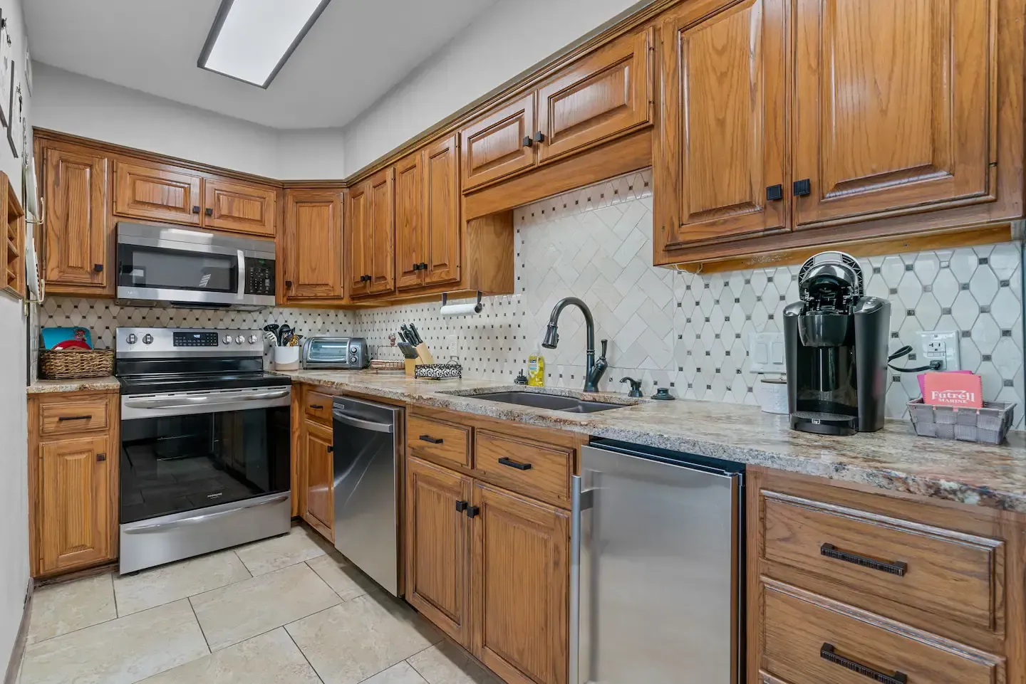 A kitchen with wooden cabinets , stainless steel appliances , and granite counter tops.