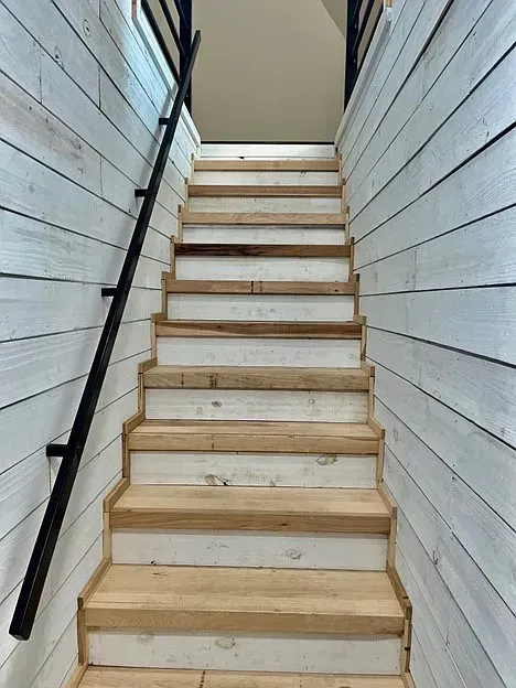 The stairs are made of wood and have a black railing.