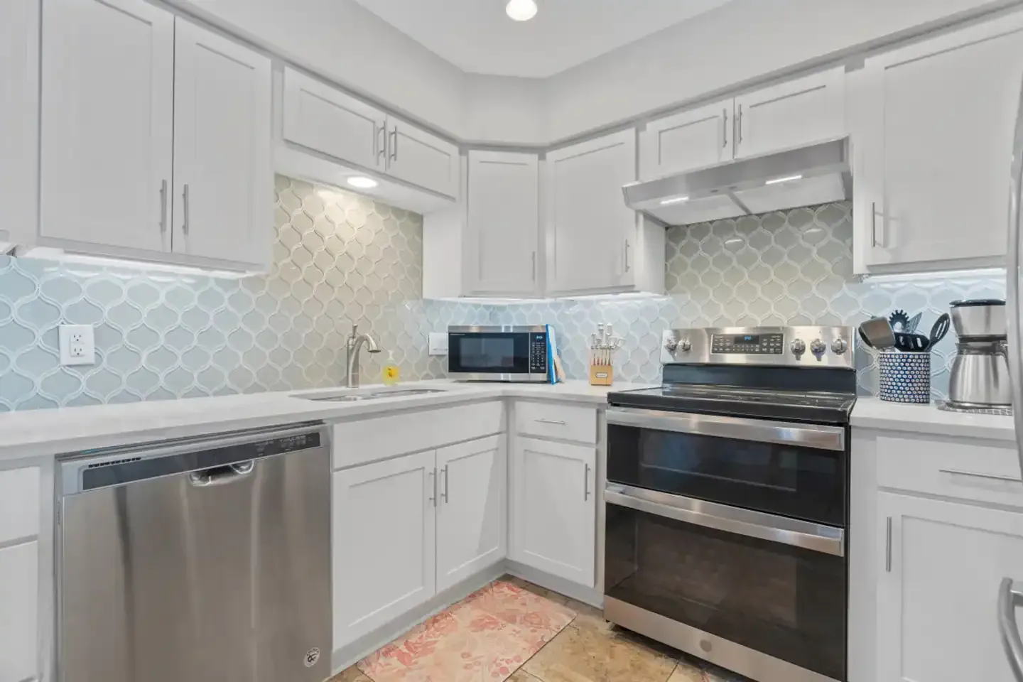 A kitchen with stainless steel appliances and white cabinets.