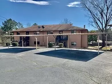 A large apartment building with a covered parking lot in front of it.