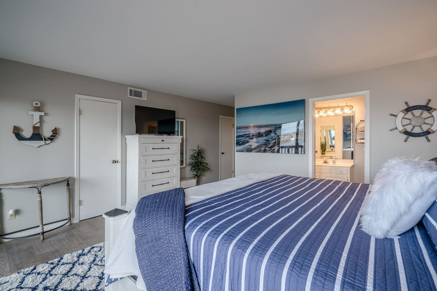 A bedroom with a king size bed , dresser , and television.