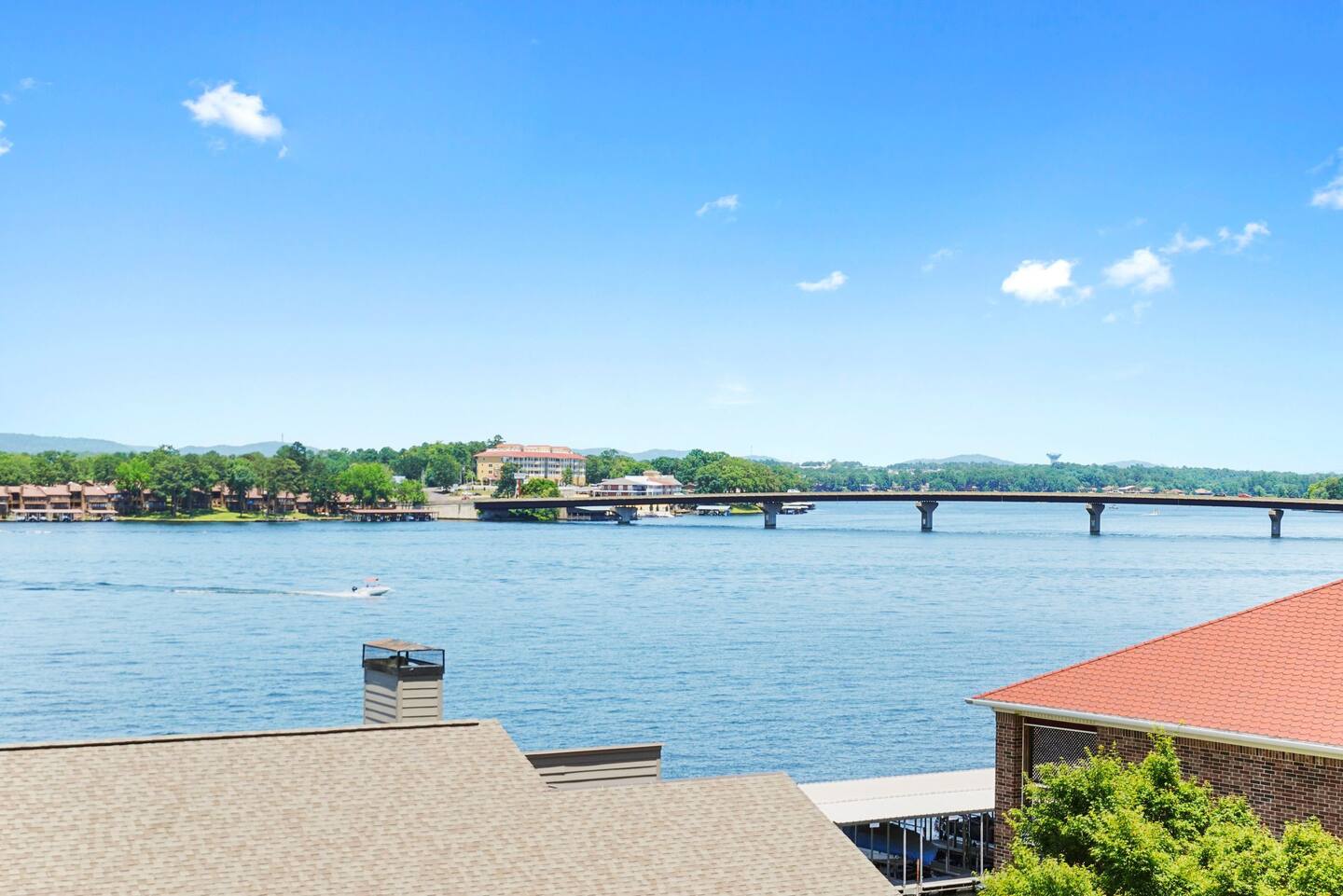 A view of a lake from a house with a bridge in the background.