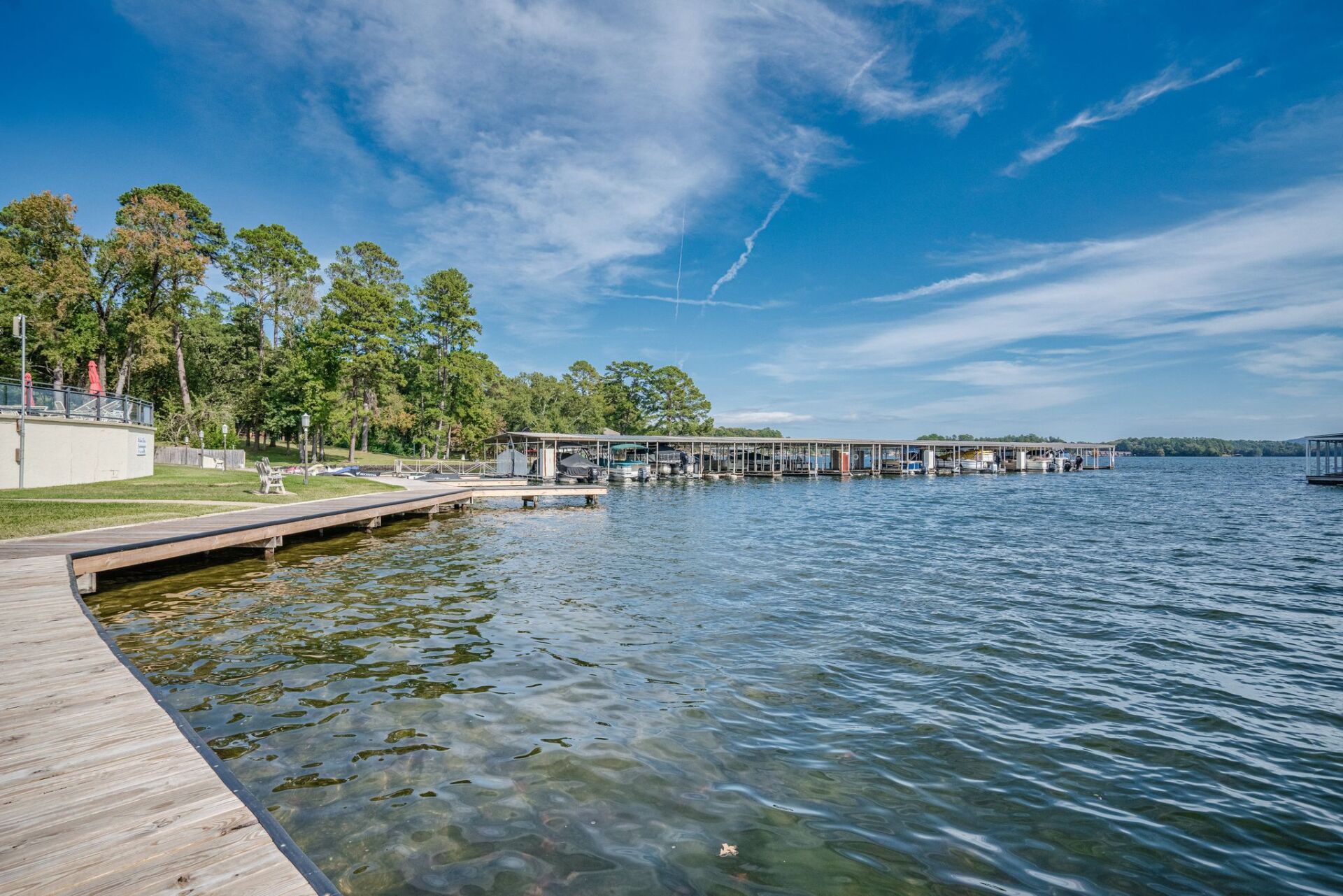 A large body of water with a dock in the foreground and trees in the background.