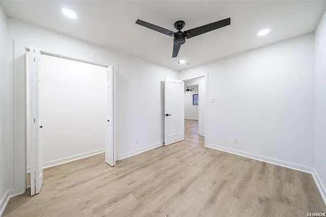 An empty bedroom with hardwood floors and a ceiling fan.