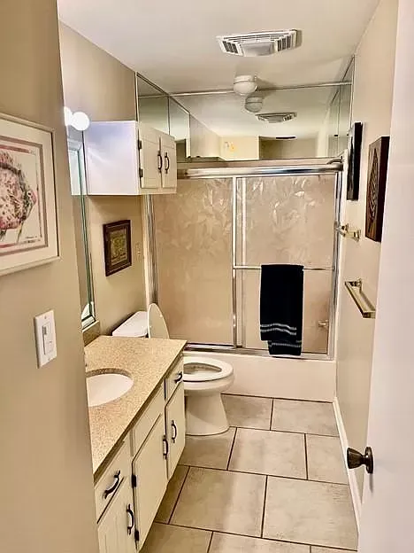 A bathroom with a toilet , sink , mirror and shower stall.