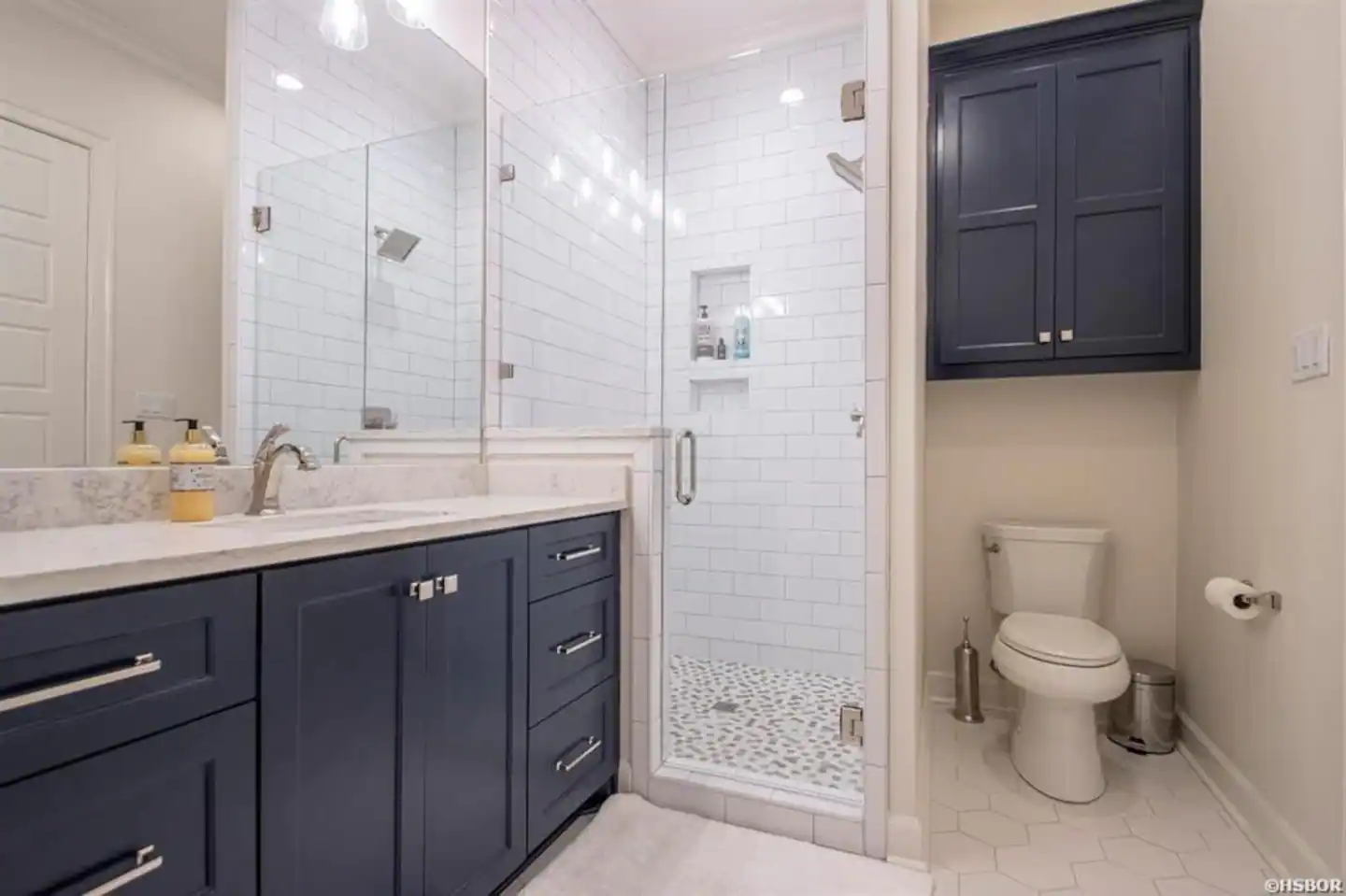 A bathroom with a toilet , sink , mirror and walk in shower.