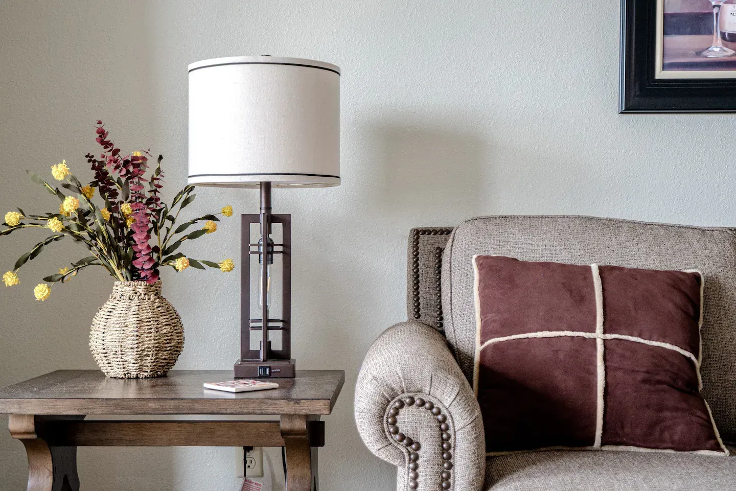 A living room with a couch a lamp and a vase of flowers