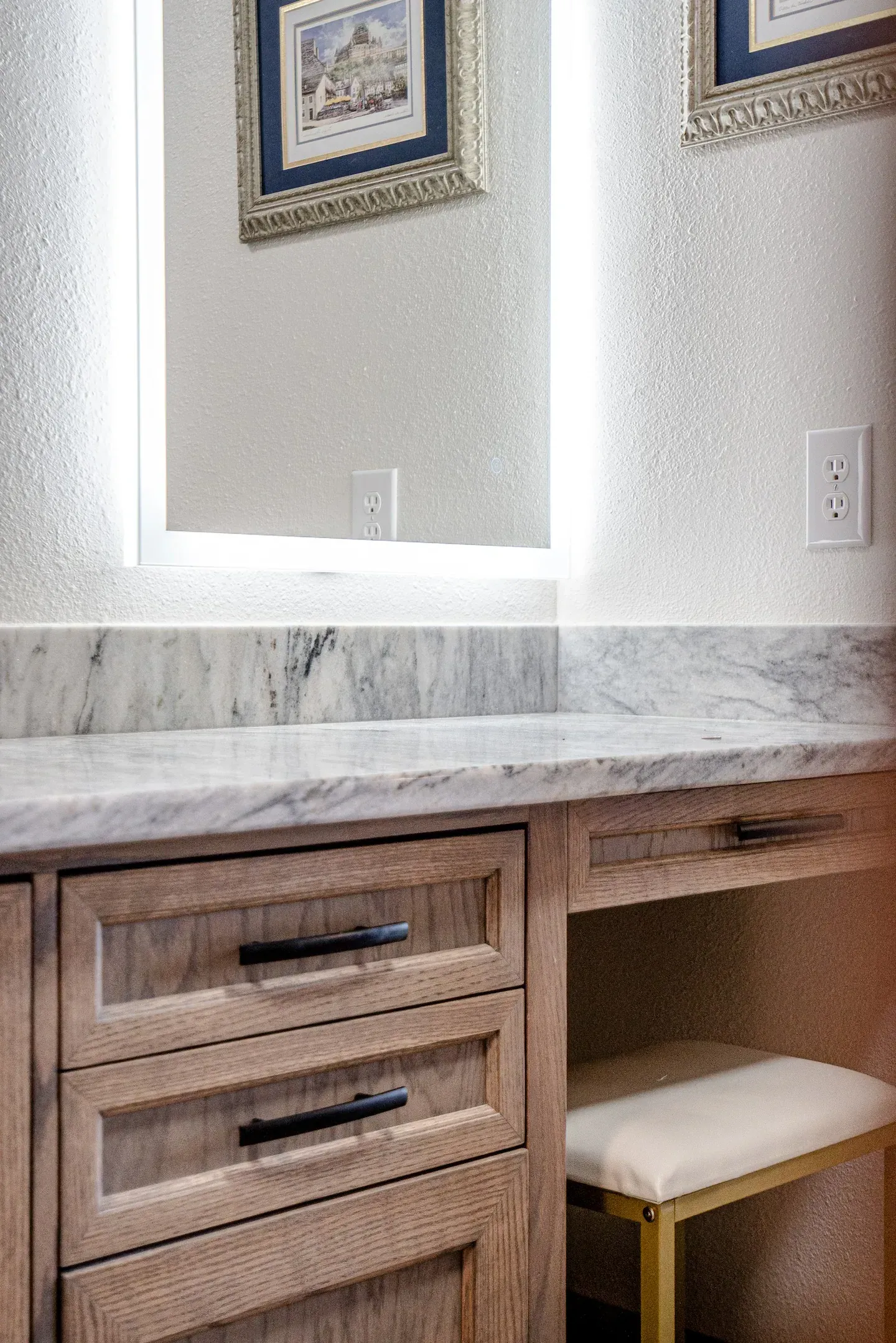 A bathroom vanity with two mirrors and a stool.