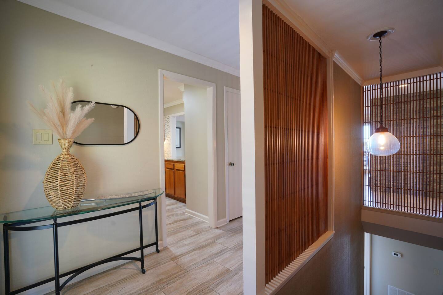 A hallway with a glass table and a mirror.