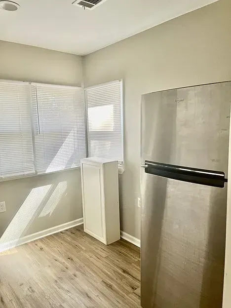 A kitchen with a stainless steel refrigerator and a window.