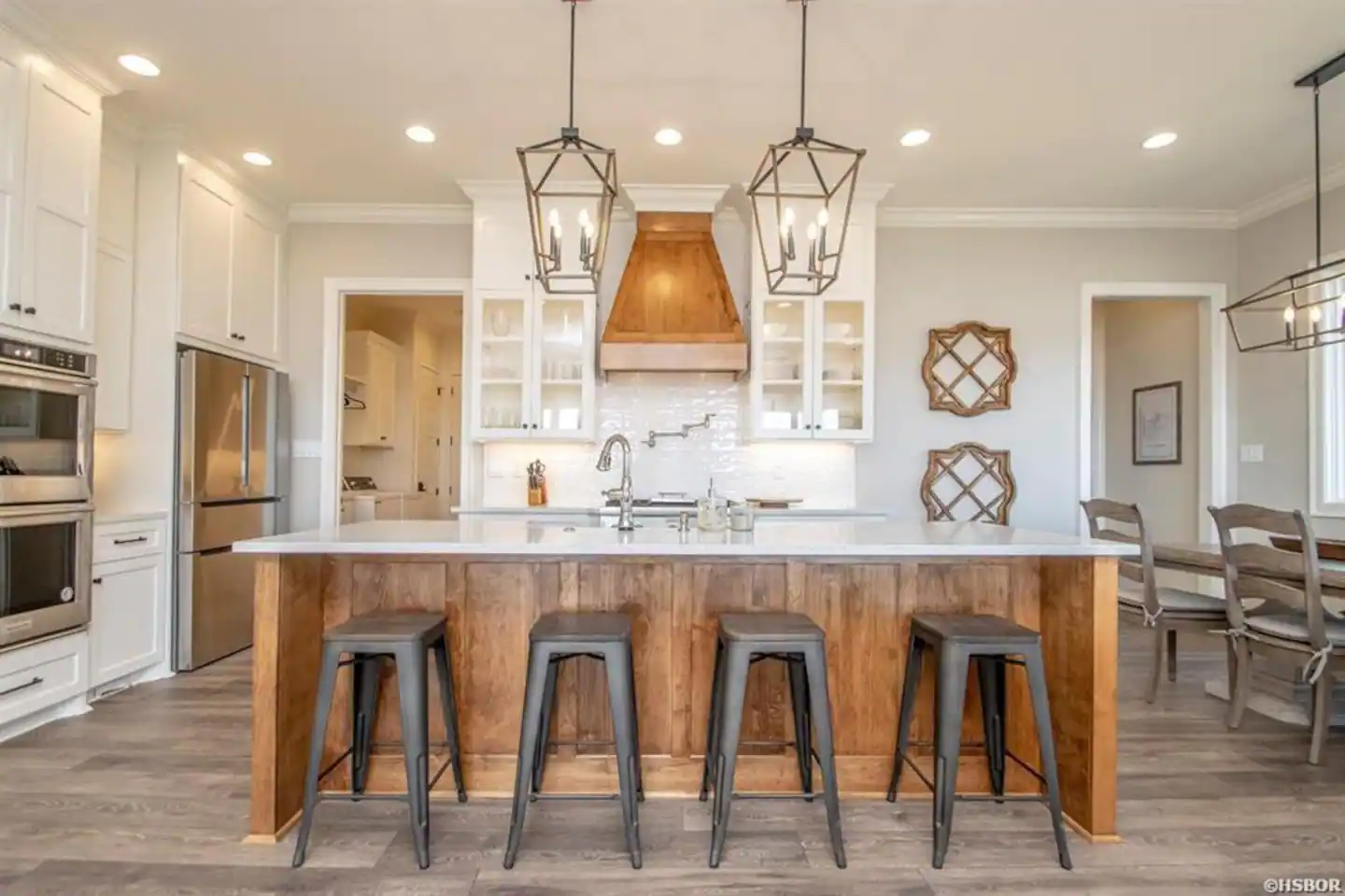 A kitchen with a large island and stools in it.