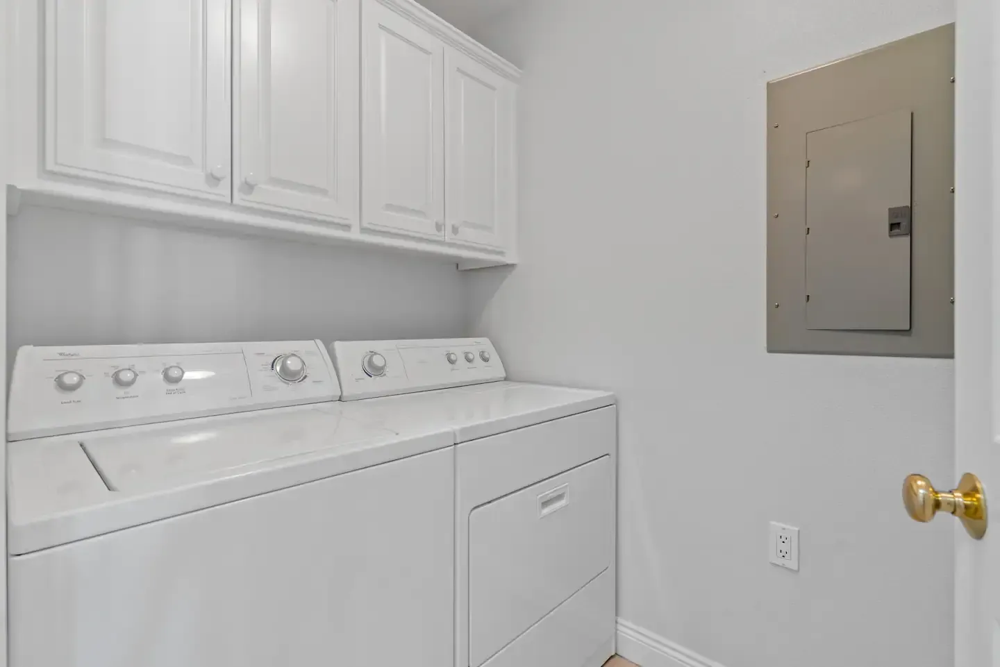 A laundry room with a washer and dryer and white cabinets.