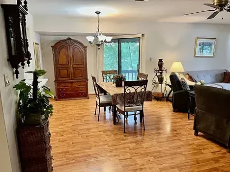 Open-concept living space with dining table, hutch, sliding door, and two armchairs.