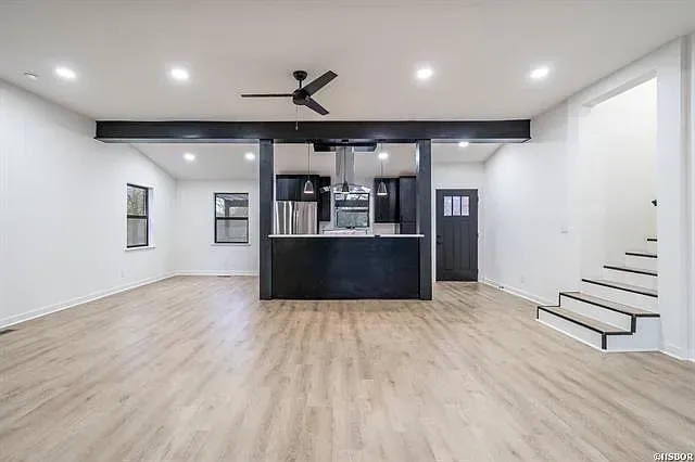 A large empty room with hardwood floors and a ceiling fan.