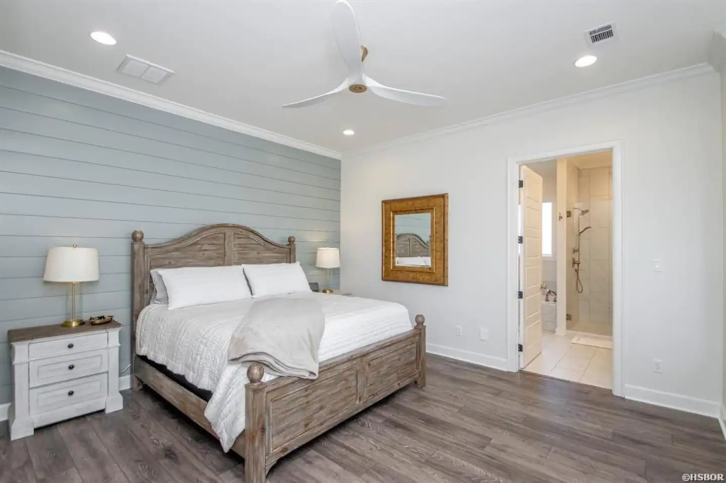 A bedroom with a king size bed and a ceiling fan.