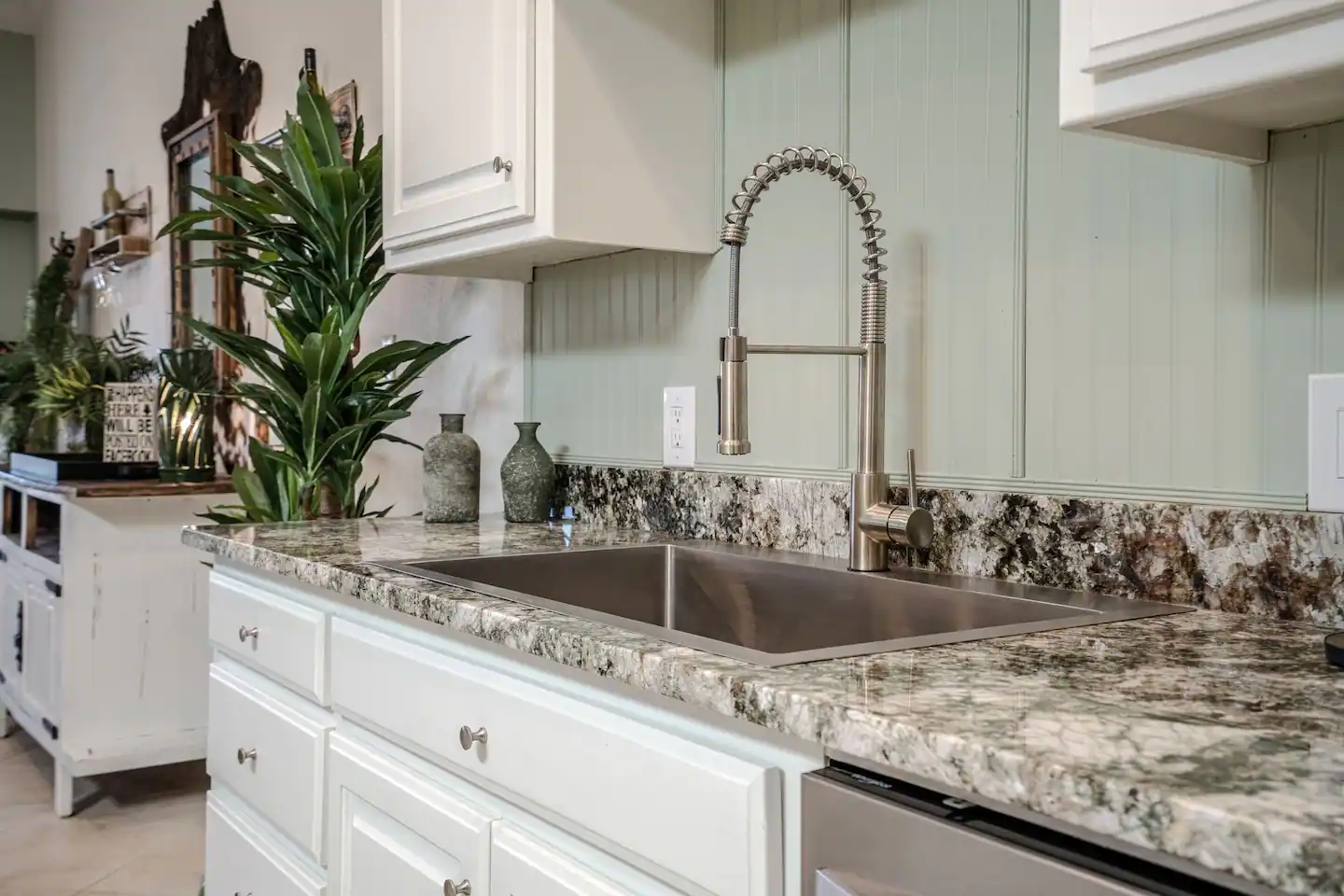 A kitchen with a stainless steel sink and granite counter tops.