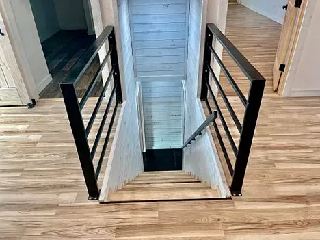 A staircase leading up to the second floor of a house with a black railing.