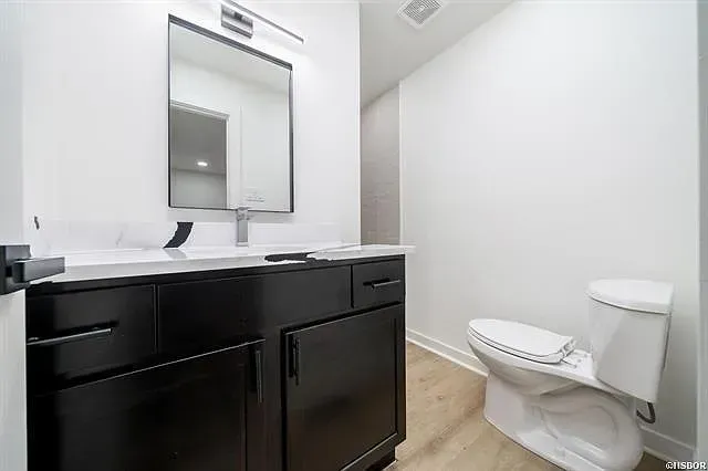A bathroom with a toilet , sink and mirror.