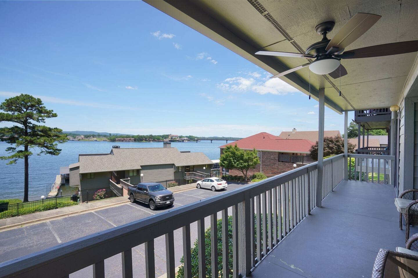 A balcony overlooking a lake with a ceiling fan