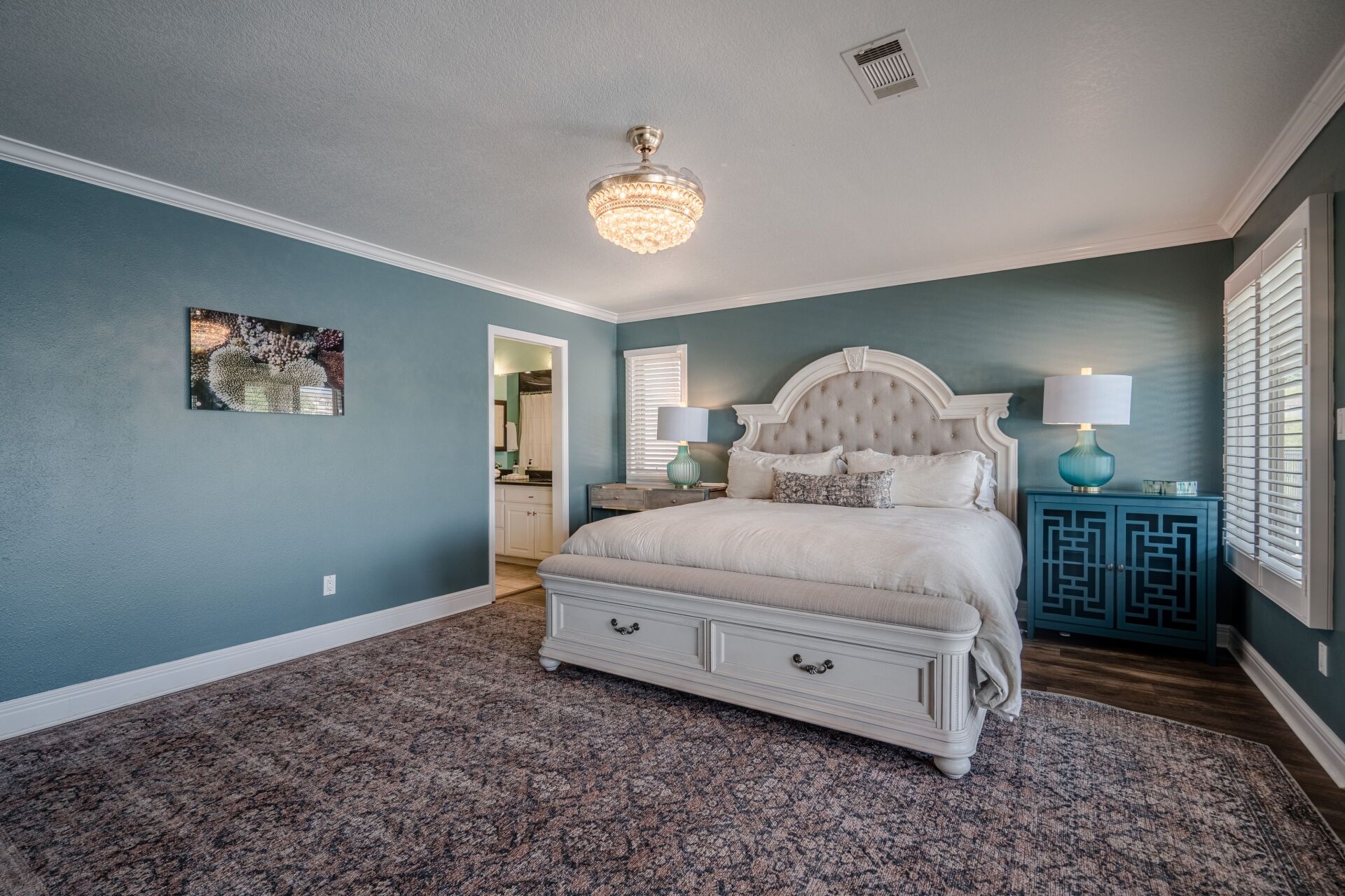 A bedroom with a king size bed , nightstand , lamps and blue walls.