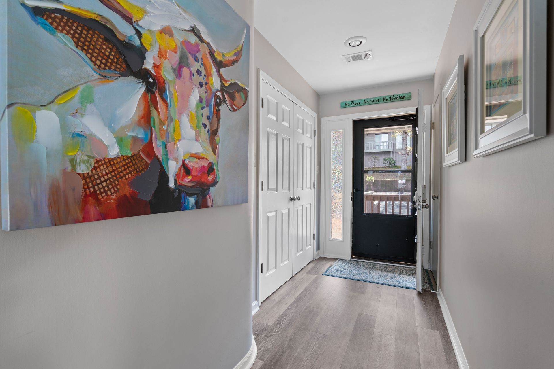 A hallway with a painting of a cow on the wall.