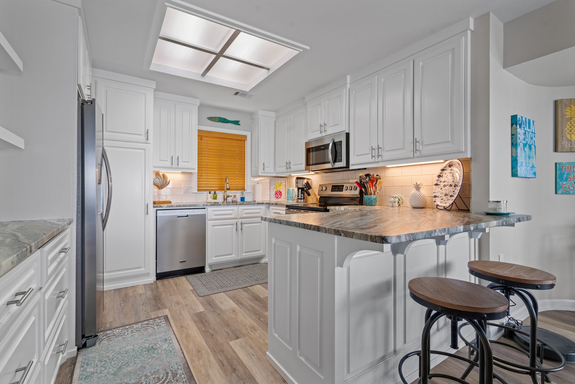 A kitchen with white cabinets , granite counter tops , stainless steel appliances and a large island.