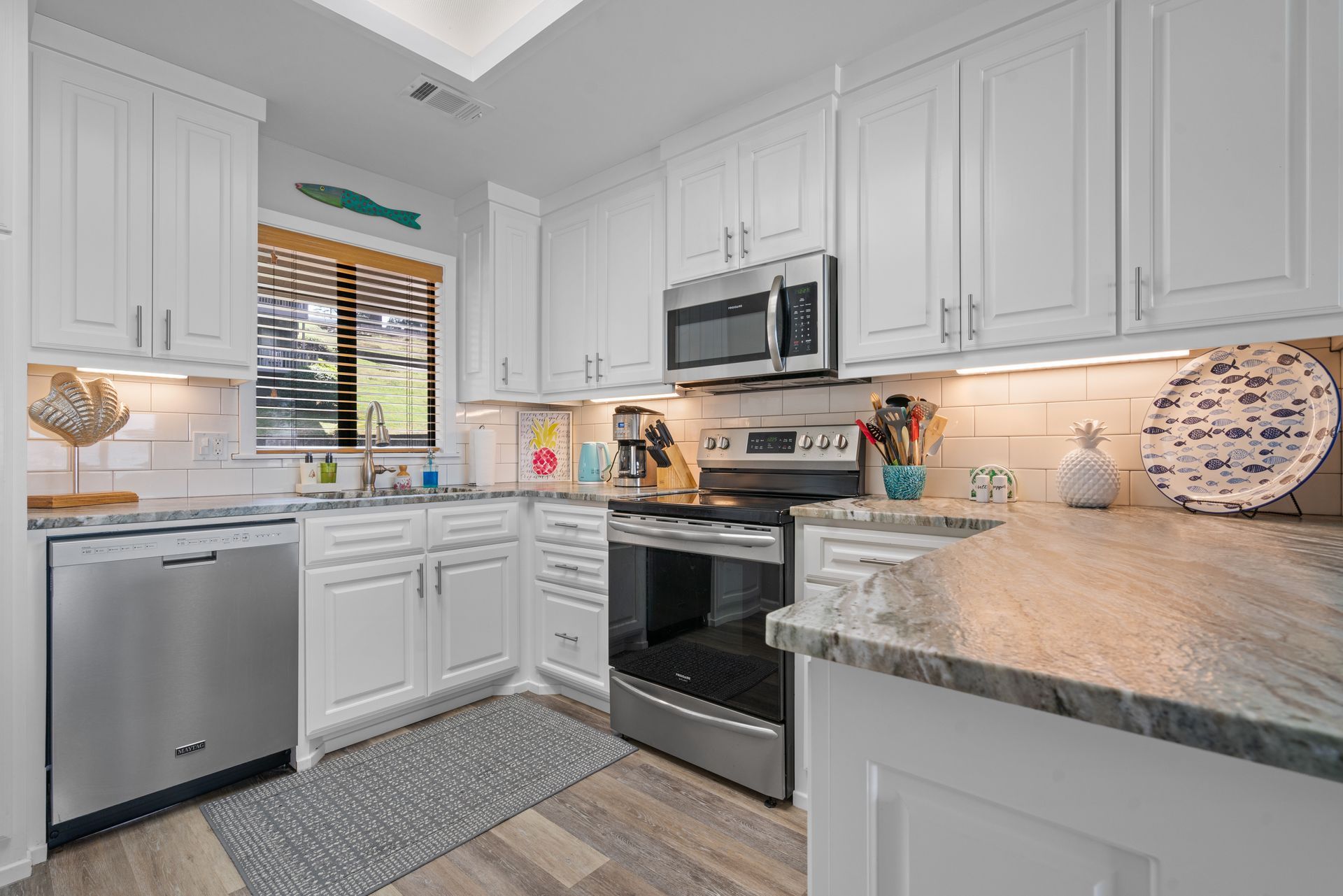 A kitchen with white cabinets , stainless steel appliances , and granite counter tops.