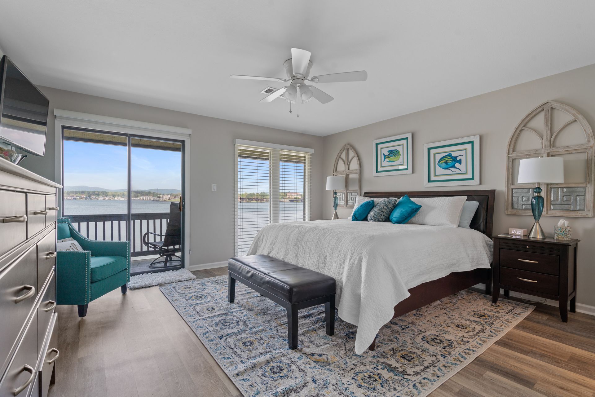 A bedroom with a large bed , a bench , a chair and a ceiling fan.