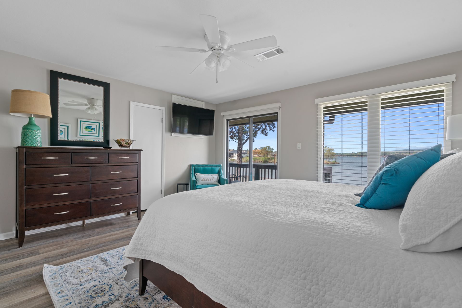 A bedroom with a king size bed , dresser , mirror and television.