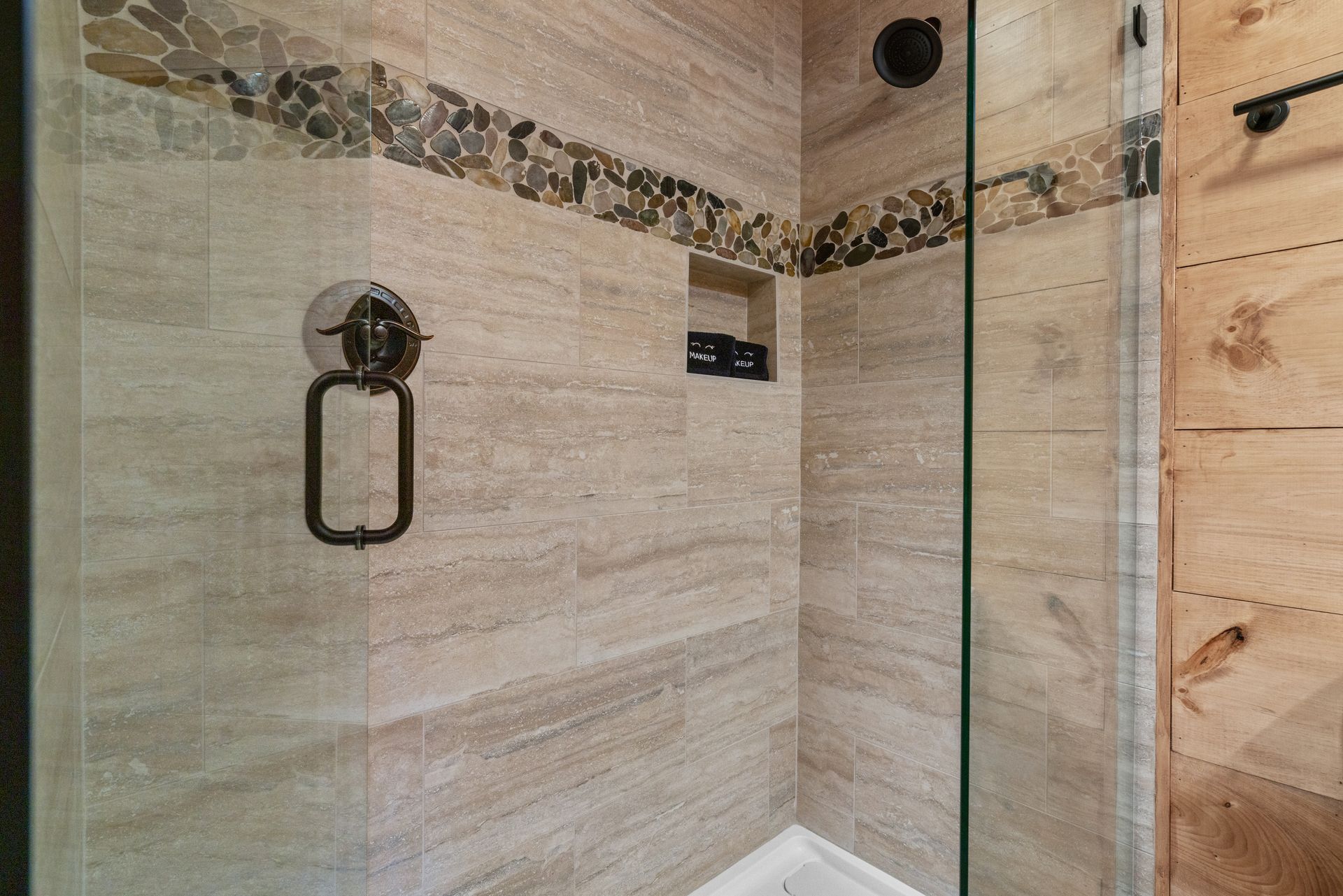 A bathroom with a walk in shower and a glass door.