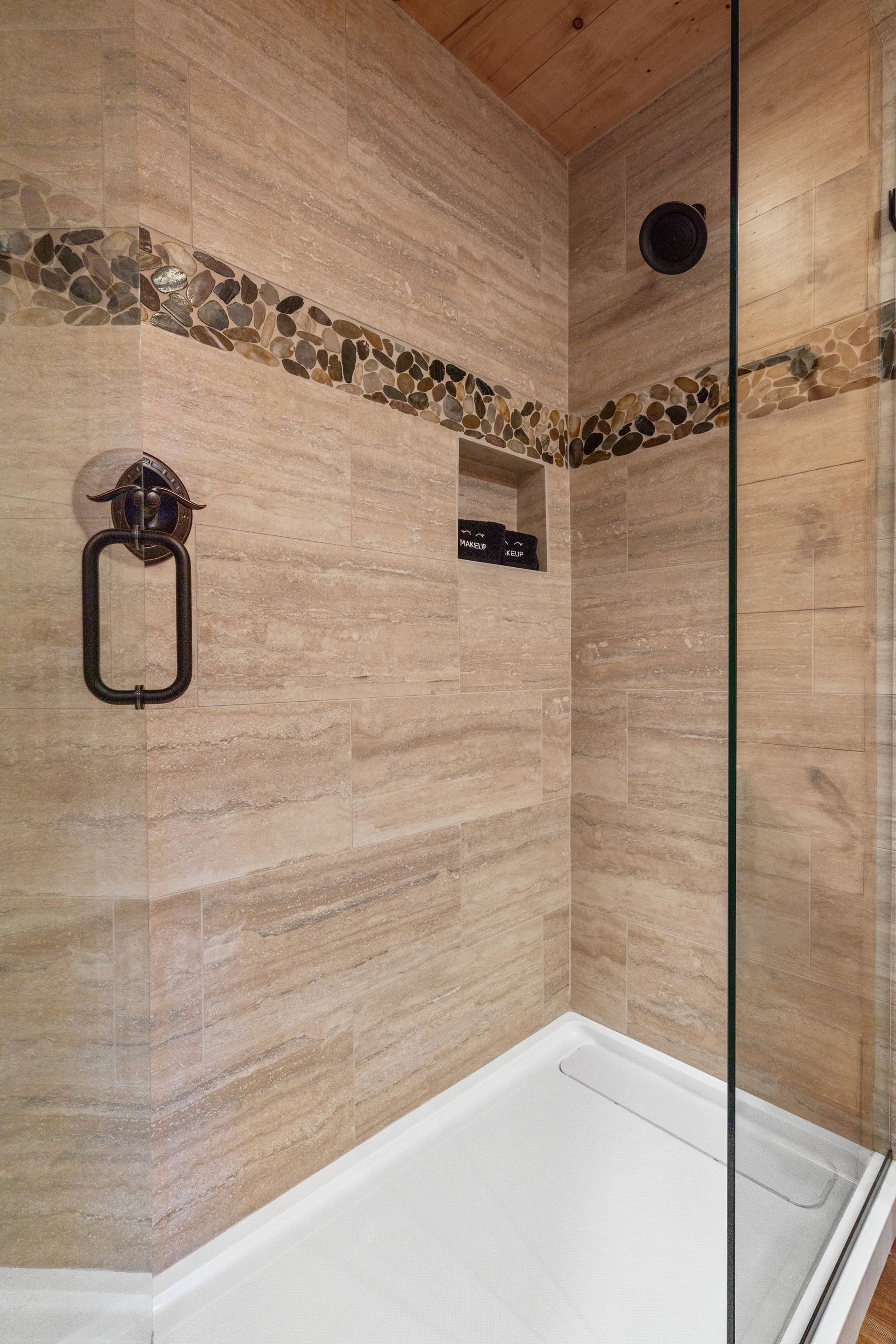 A bathroom with a walk in shower and a tiled wall.